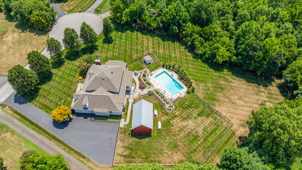 Aerial property photograph supplied for the Owings community guide, showing a home, lawn, pool and surrounding trees